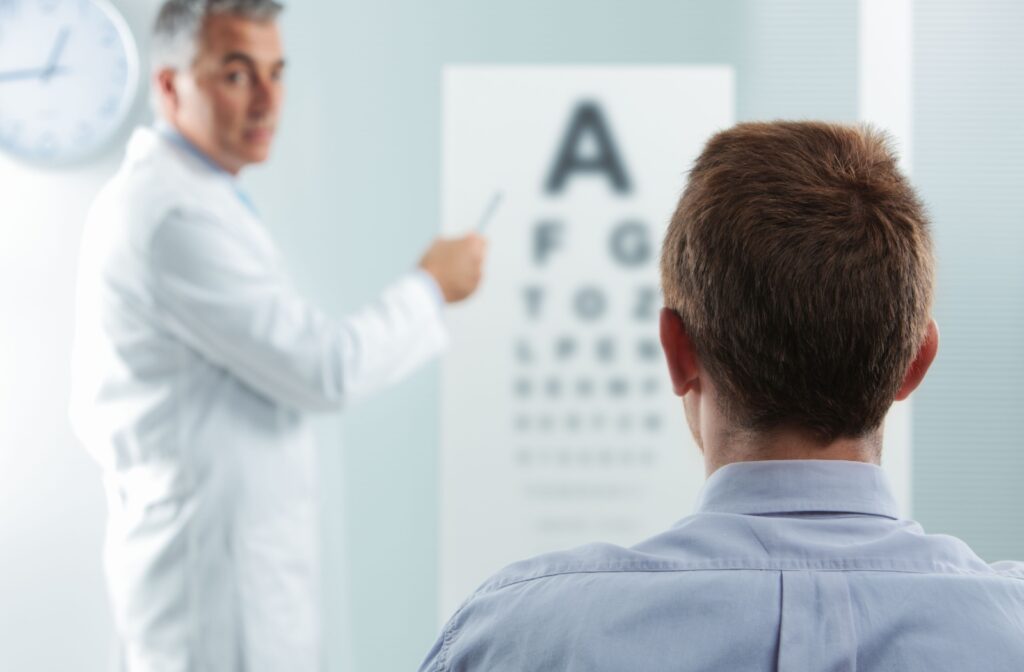 A person at their first eye exam, reading at eye chart with an optometrist pointing to the different letters on the chart.