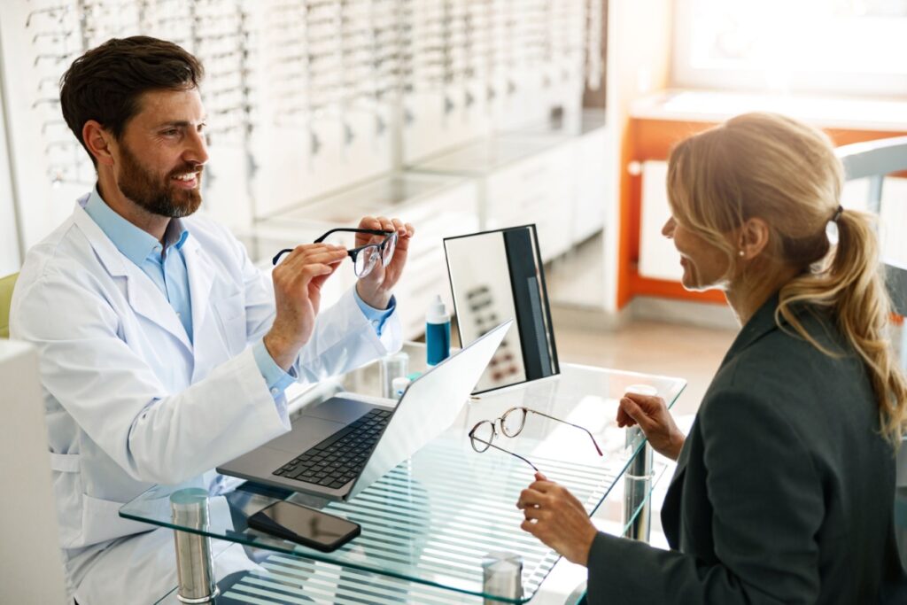 An optician showing an eye care patient their new frames.