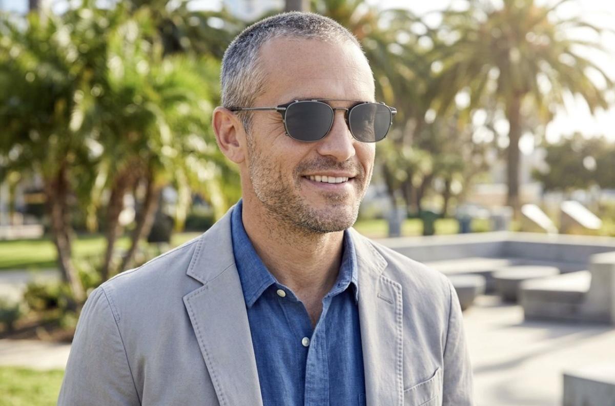A person wearing clip on sunglasses over their prescription glasses while outside.
