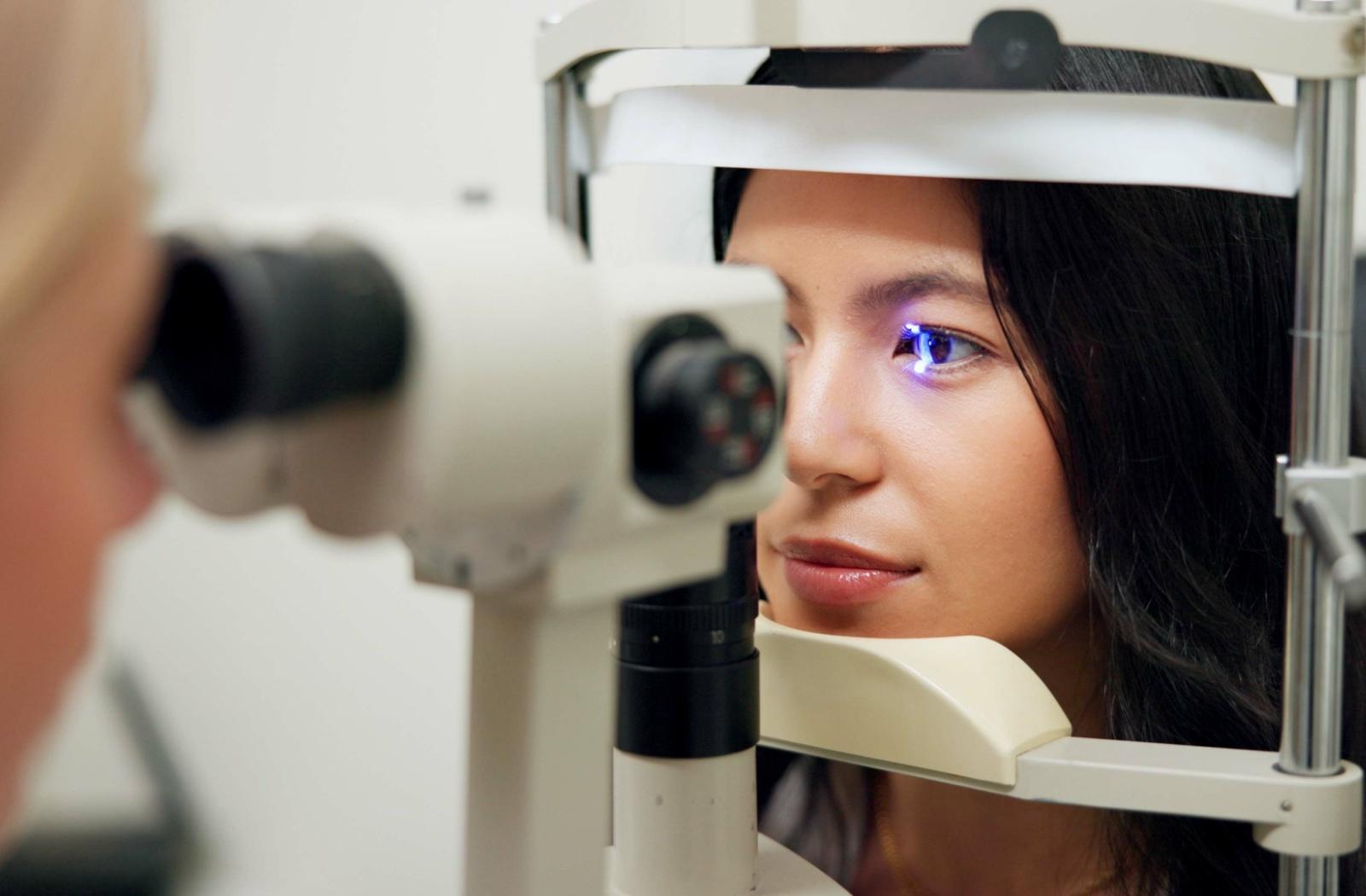 A patient having their eyes examined by an eye doctor using a slit lamp, which shines a light into the patient's eye.
